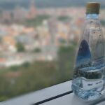 Bottiglia d'acqua e bicchiere su un tavolo, simbolo di idratazione al risveglio.