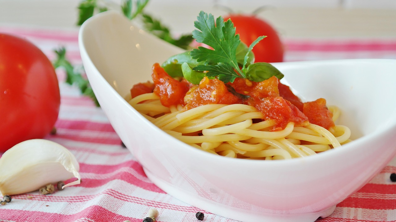 Pasta al pomodoro servita in un piatto, con ingredienti freschi accanto per una preparazione sana.