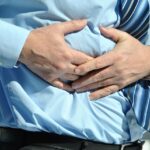 Immagine di una persona che tiene la mano sulla pancia, rappresentando il disagio del reflusso gastrico.