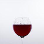 Bicchiere di vino rosso con una bottiglia, simbolo di salute e resveratrolo per il cuore.