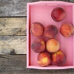 Pesche fresche su un tavolo, simbolo dei benefici per la pressione sanguigna.