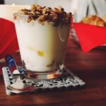 Un bicchiere di yogurt su un tavolo, simbolo di un'abitudine serale per il metabolismo.